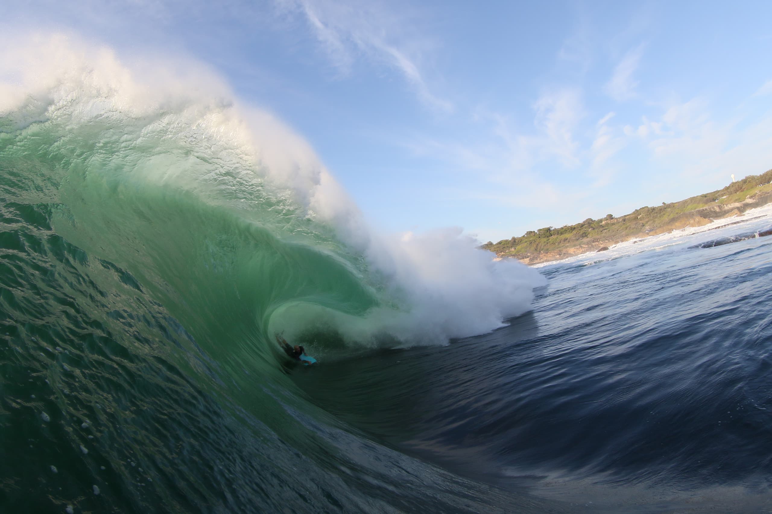 A bodyboarder riding through white water and spray.