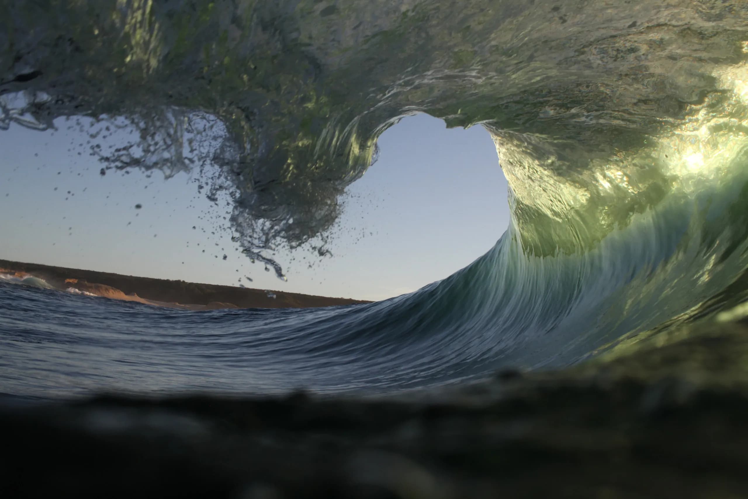 Sunlight passing through the lip of a breaking green wave.