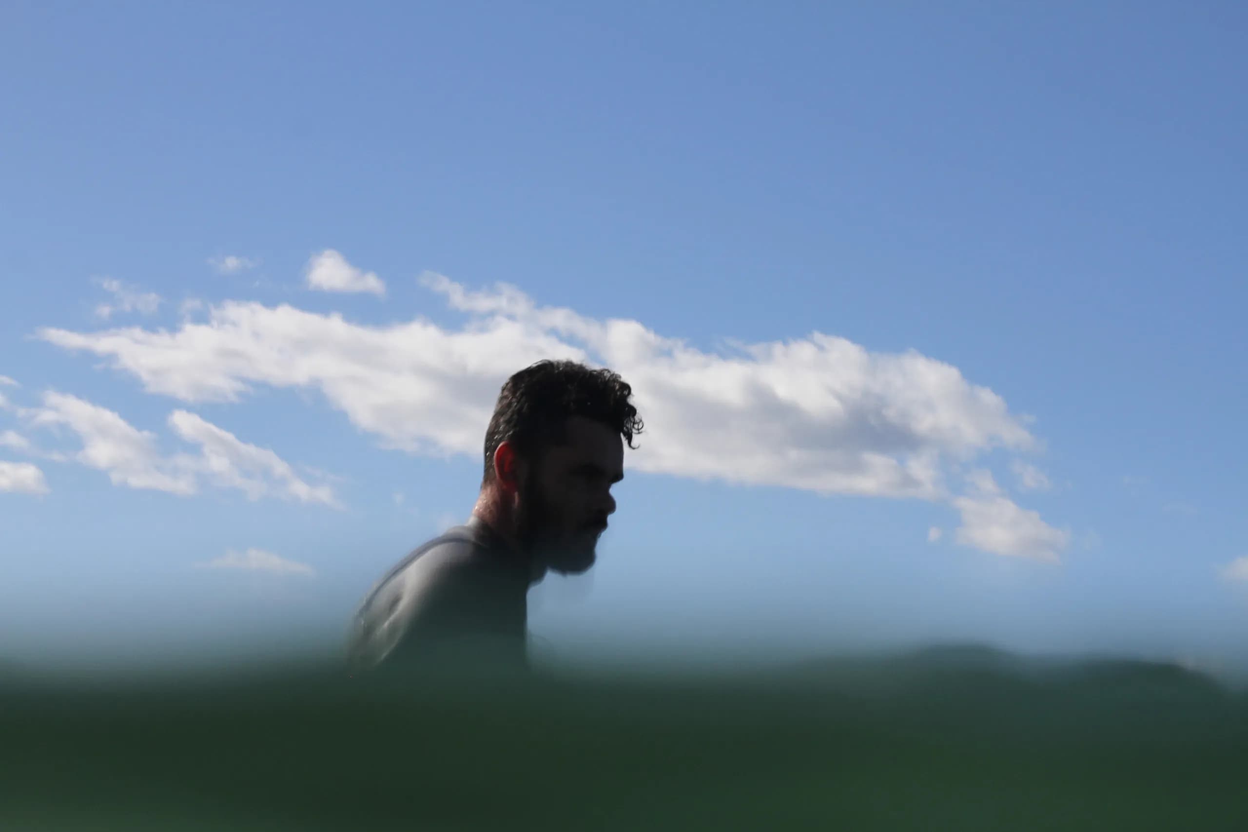A swimmer emerging from calm water beneath a clear sky.