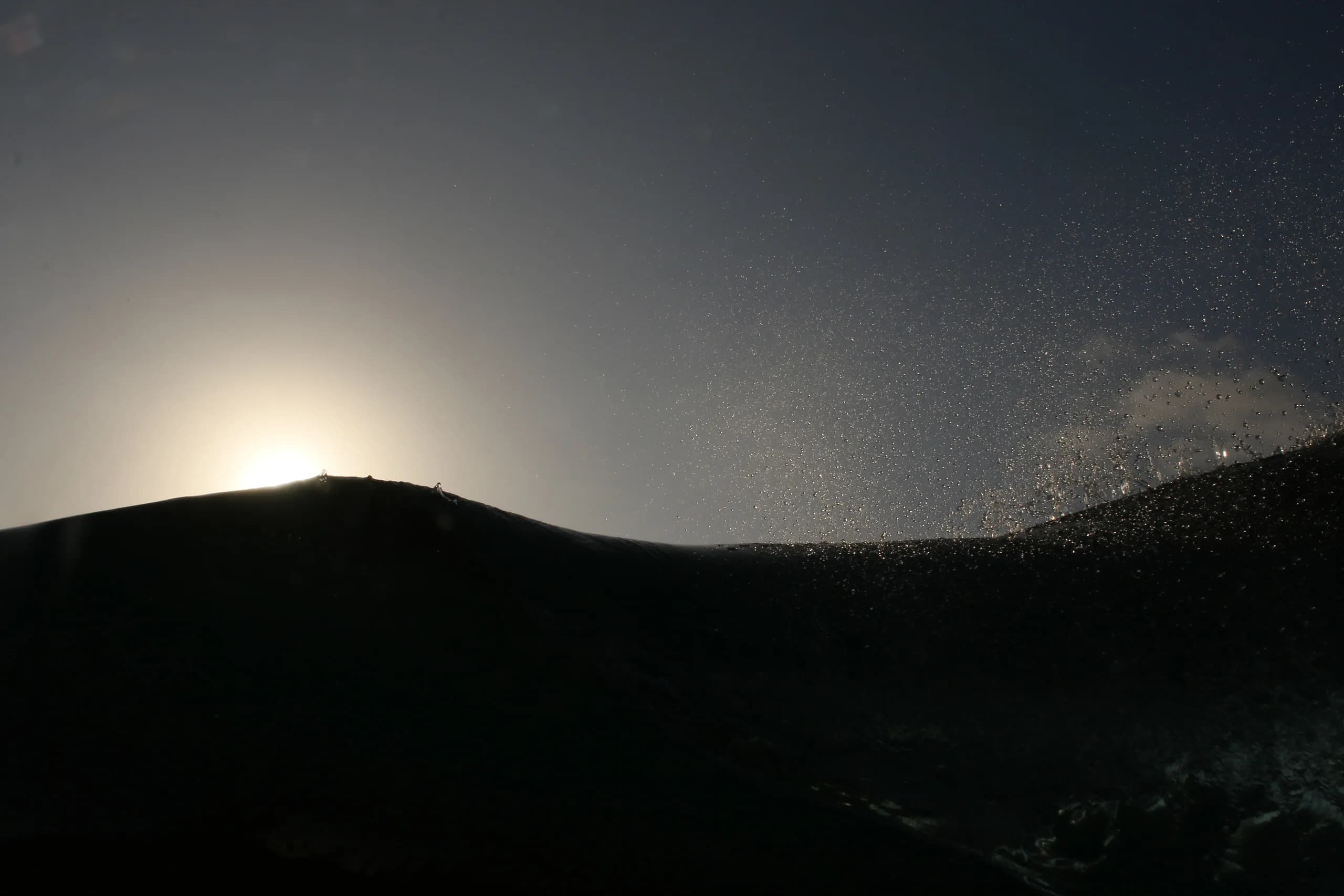 A dark coastal ridge silhouetted beneath the sun.