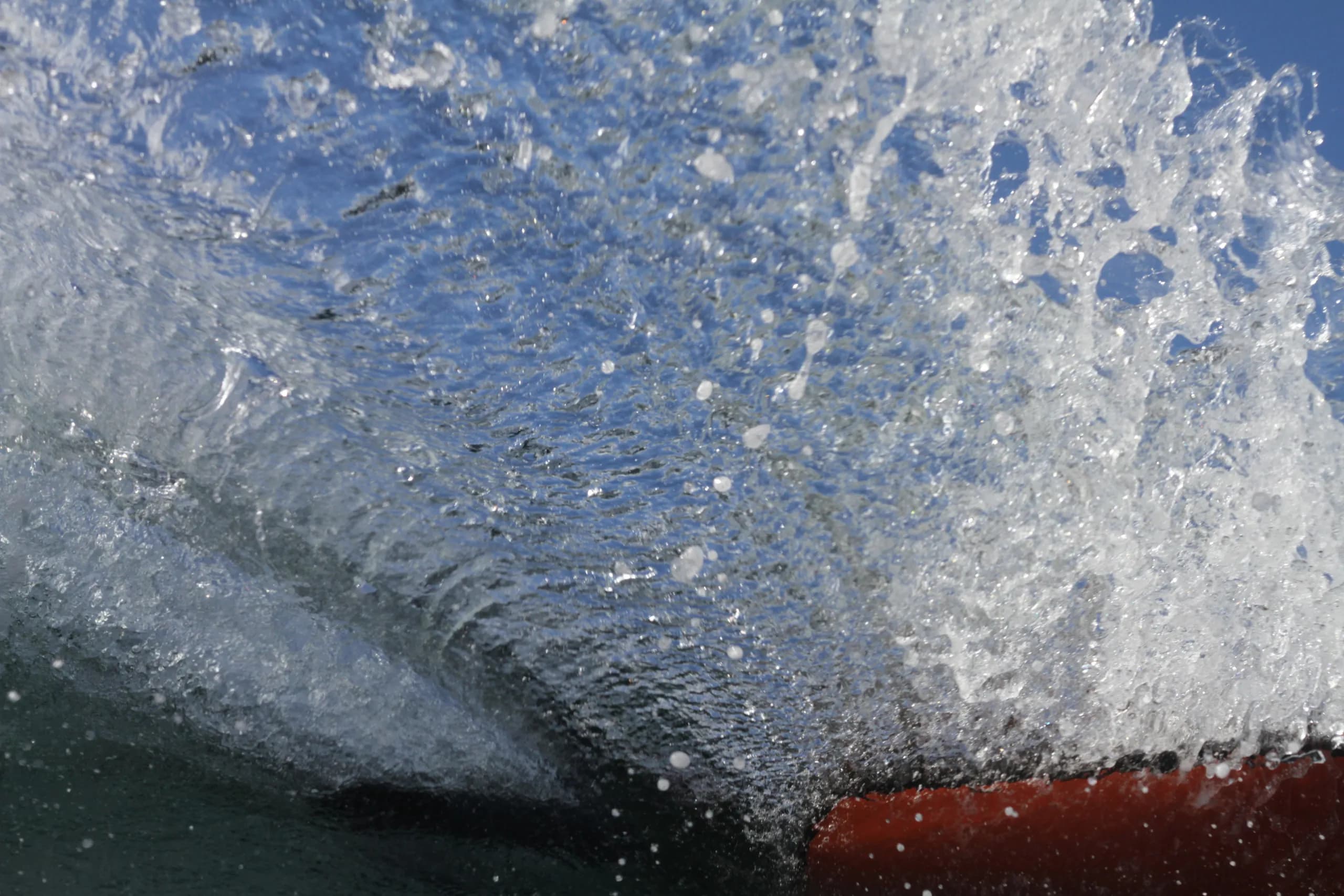 A bodyboarder and red board surrounded by white spray.