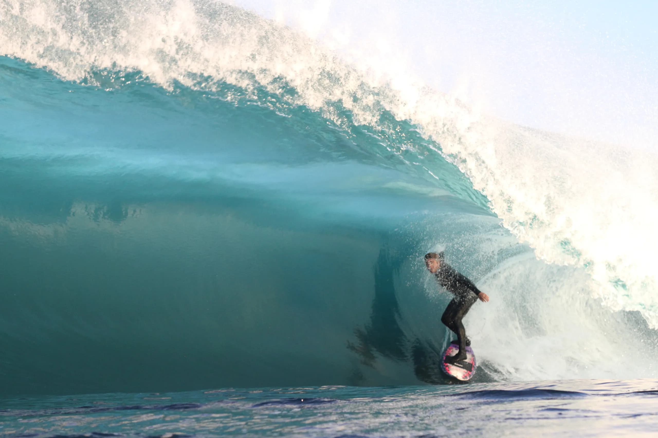 A surfer holding a line inside a clear blue barrel.