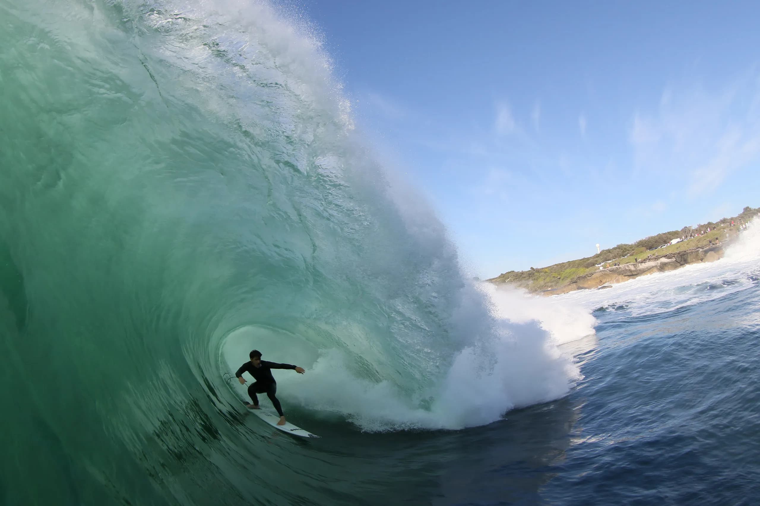 A surfer setting a line ahead of a breaking green wave.