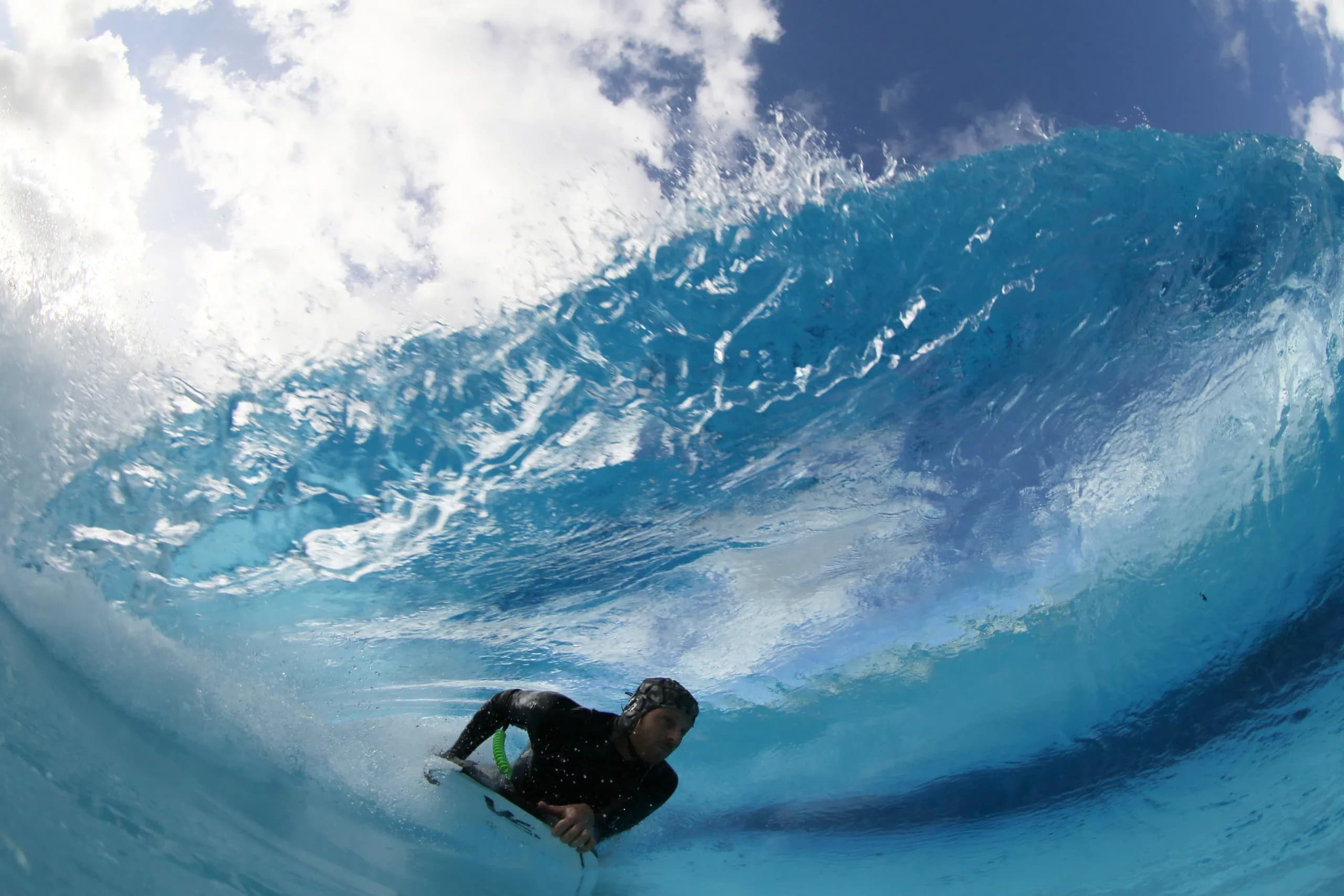 A bodyboarder cutting through a bright blue wave.