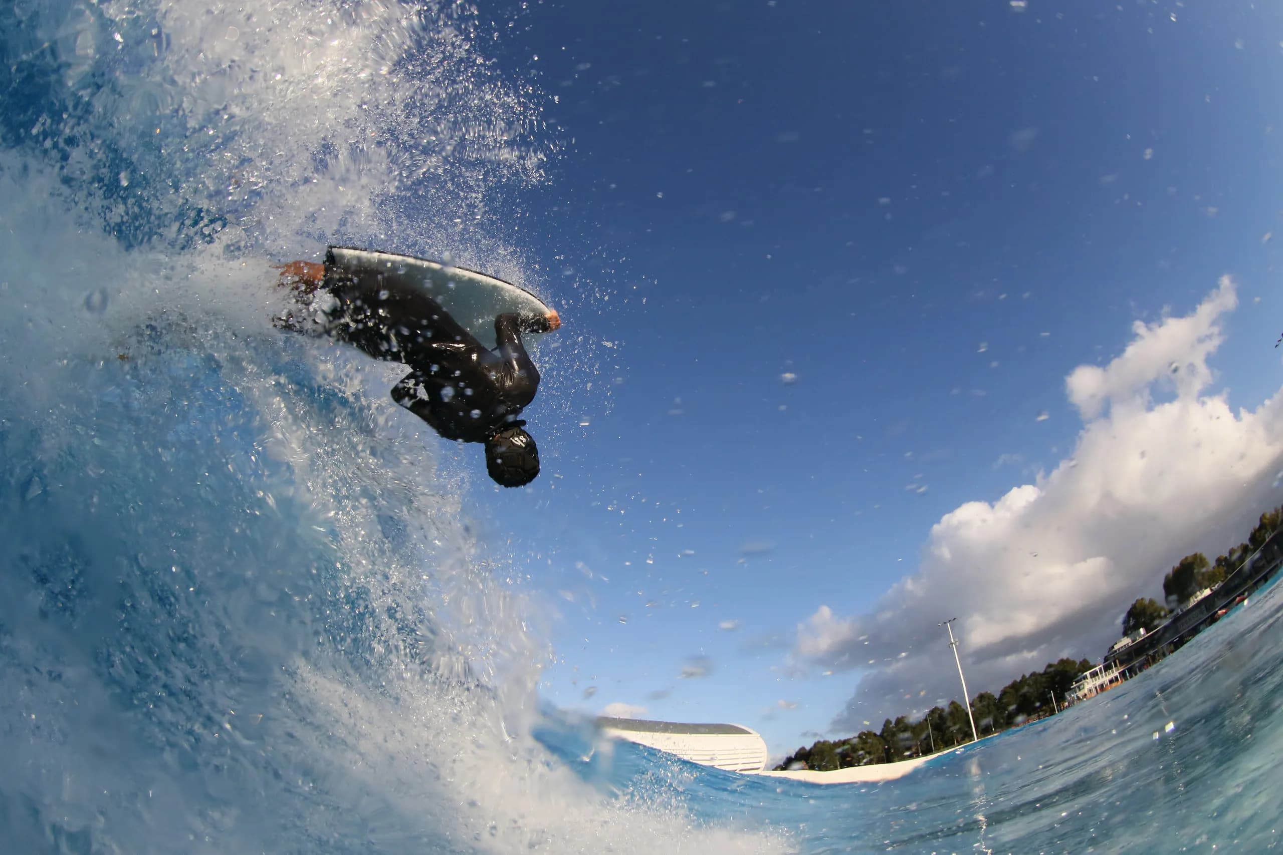 A bodyboarder airborne above a clear blue wave.