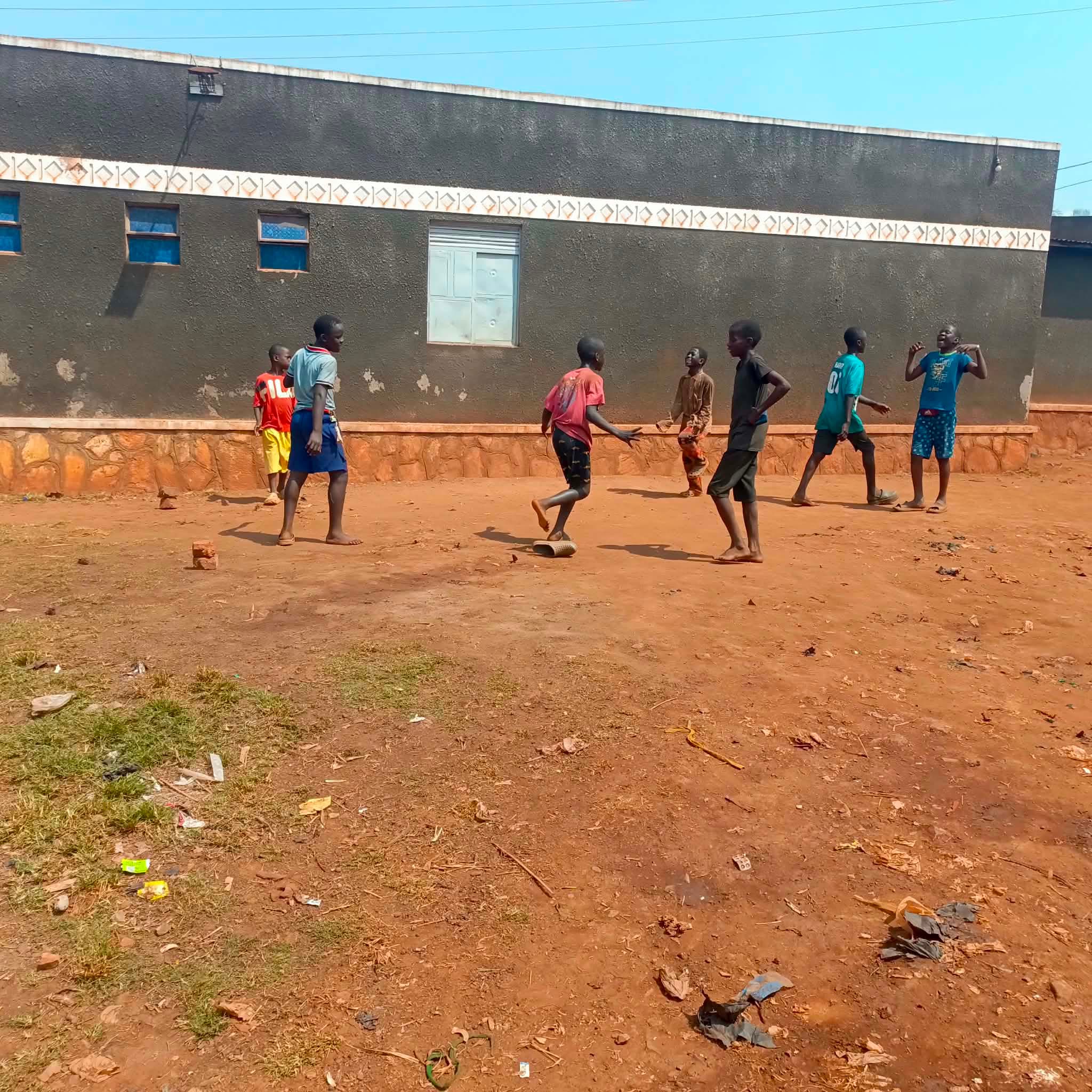Children play together on a red-earth courtyard.