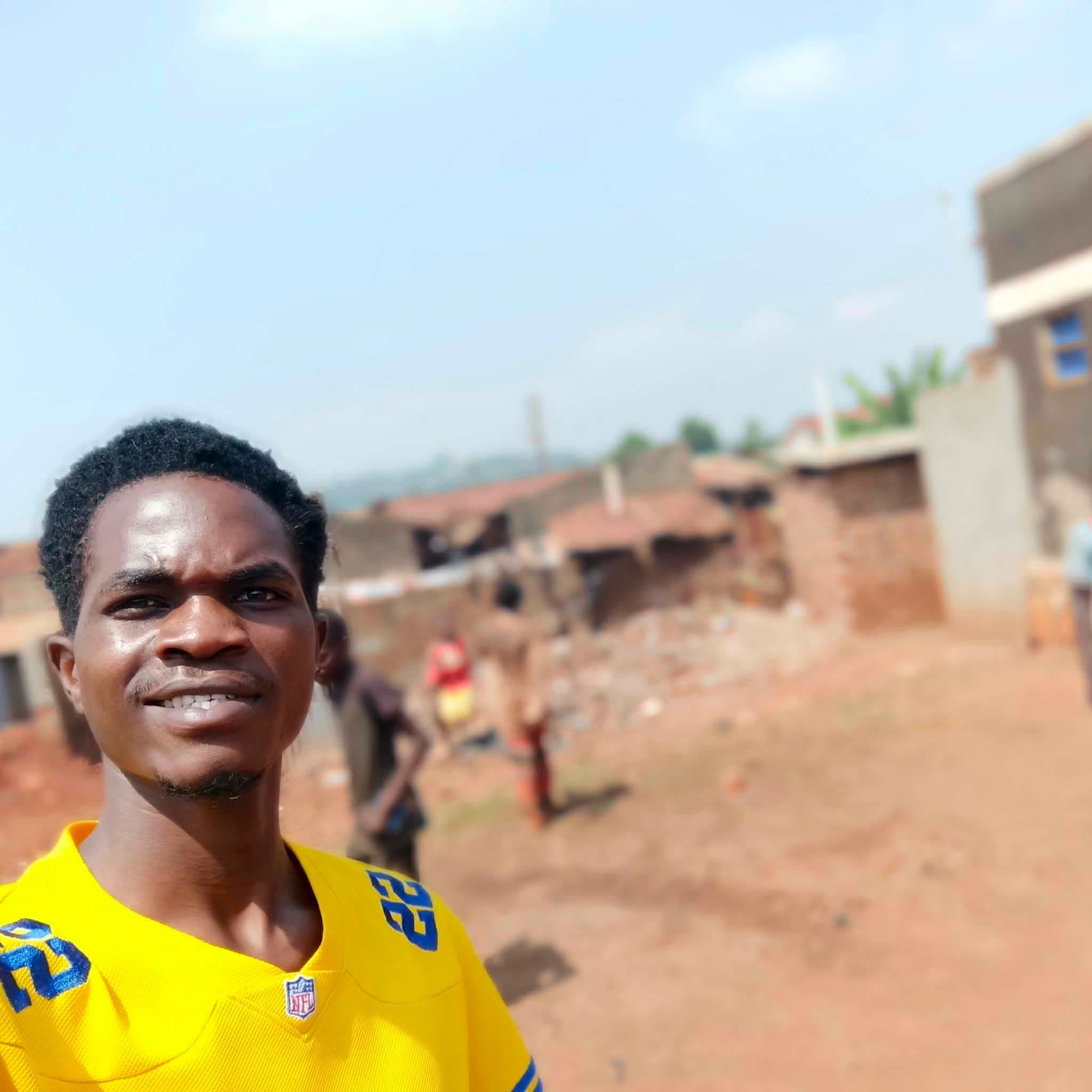 Magezi stands outdoors in a yellow shirt.